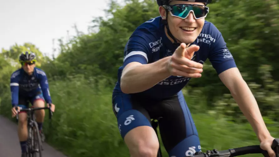A cyclist in Oxford kit riding past the camera and pointing down the lens 