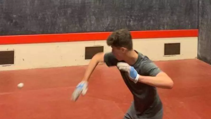 One player on a rugby fives court preparing to hit a ball