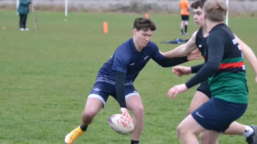Four Oxford students playing touch rugby again an opposing team on a grass pitch